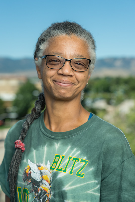 Gillian Bowser, a braid slung over her shoulder, smiling in the outdoors