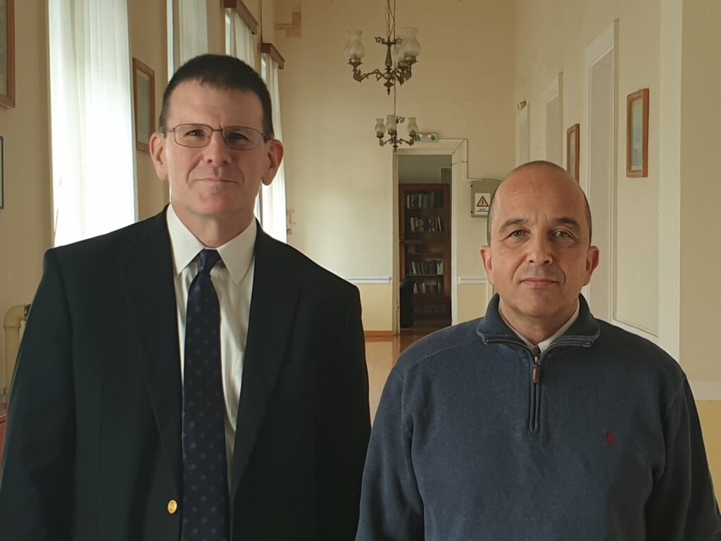 Two men standing next to each other in a hallway