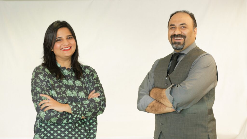 A Pakistani man and woman standing next other with their arms crossed.