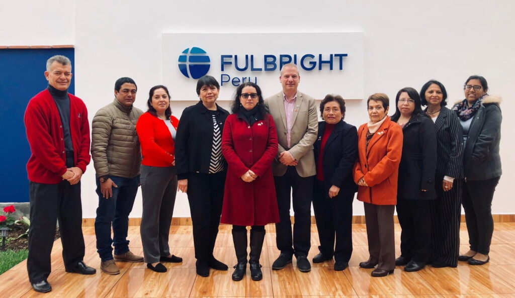 Fulbright Peru staff standing in front of the Fulbright Peru sign at the commission.