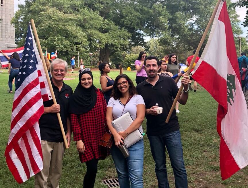 A group of students standing on campus holding a U.S. flag and a Lebanese flag.