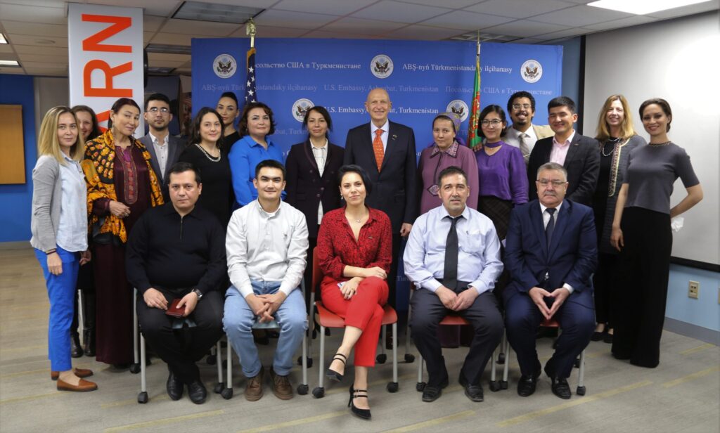 Group of people, half seated in chairs and half standing, smiling for a photo