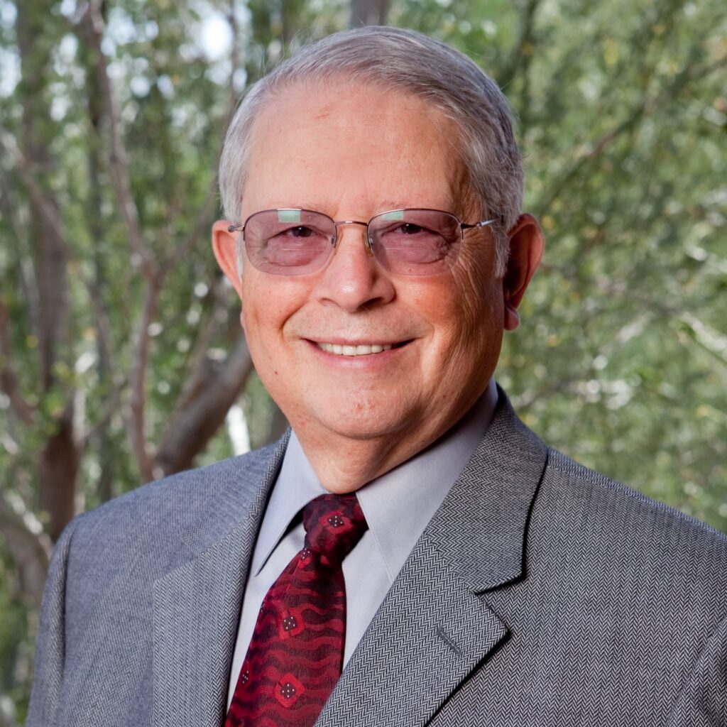 Headshot of a man with glasses, suit, and tie