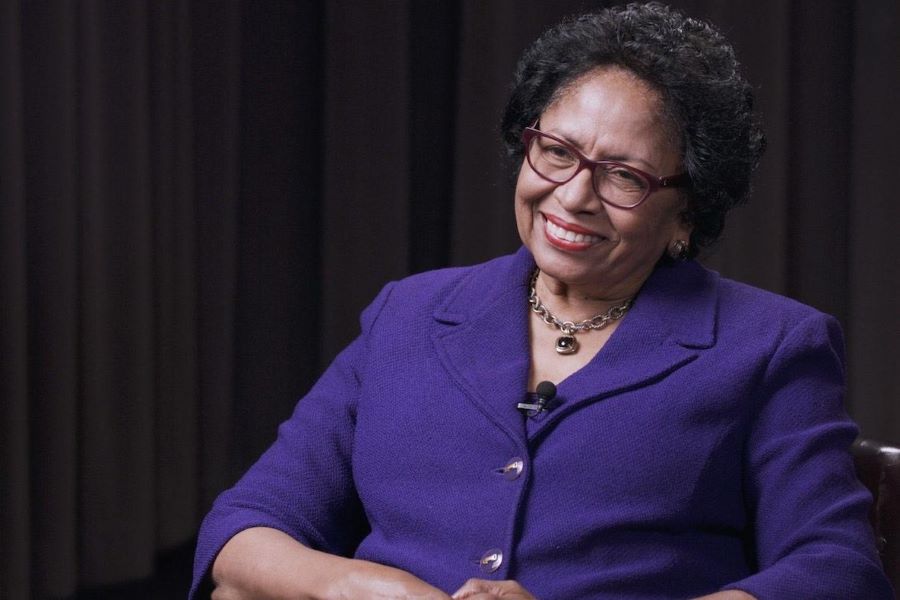 Dr. Ruth Simmons seated, wearing purple suit