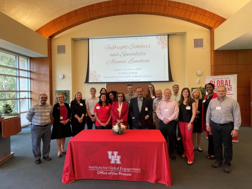 Fulbright Alumni standing standing in front of projector screen and behind table