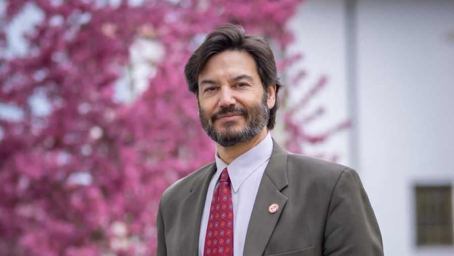 Jonathan Koppell wearing a suit standing in front of cherry tree on Montclair State University campus
