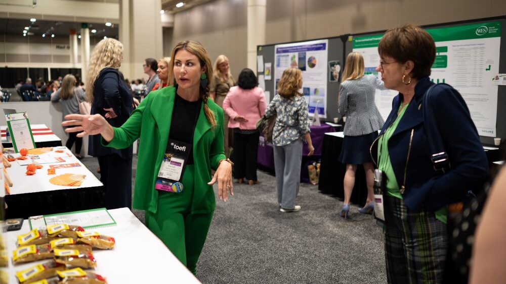 Two women at NAFSA standing by poster talking