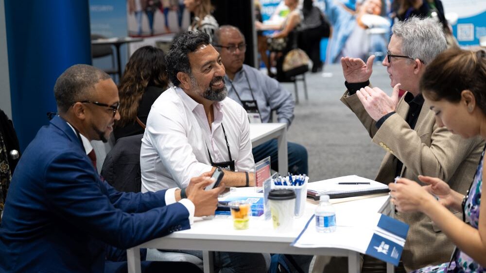 Group of NAFSA attendees sitting at table talking.