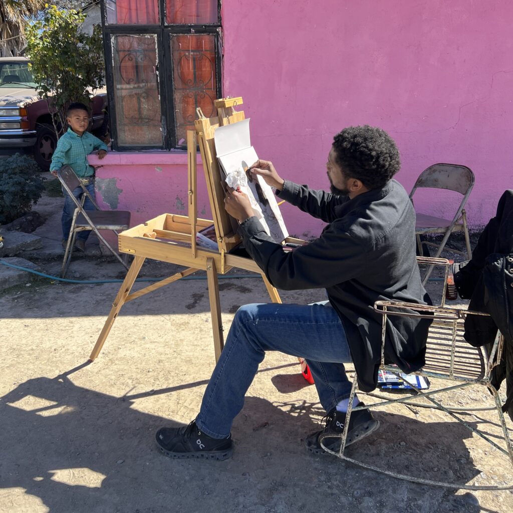 Sedrick Huckaby sitting at easel painting a women