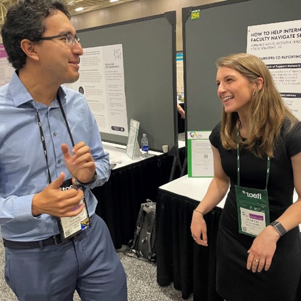 Two people in discussion in front of poster at NAFSA