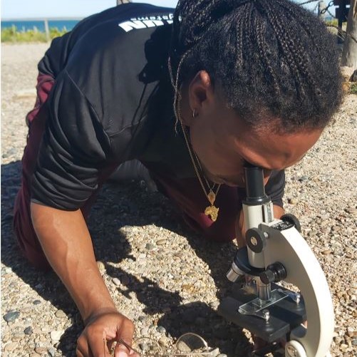 Jamil Wilson looking at algae through microscope on ground