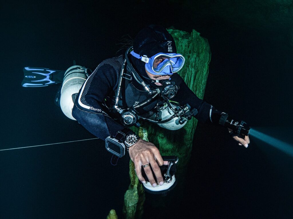 Jamil Wilson diving underwater with torch