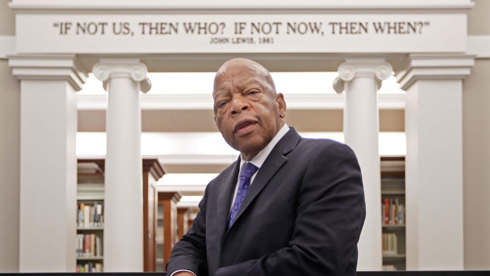 John Lewis standing under quote of his in Nashville Public Library