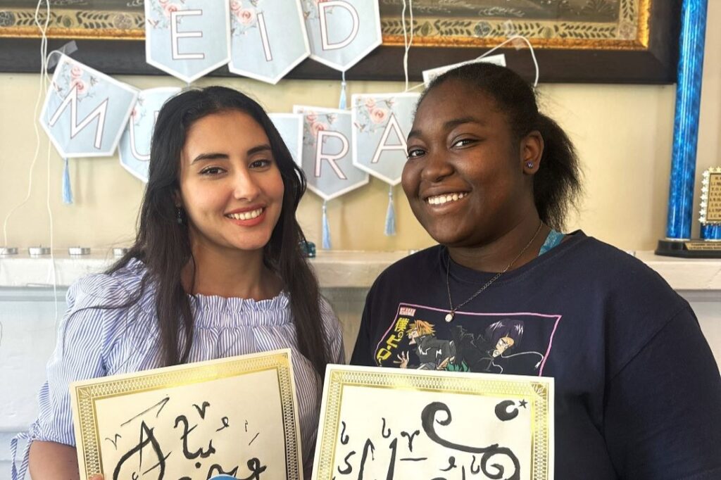 Selma Sebbane with student in front of Eid sign