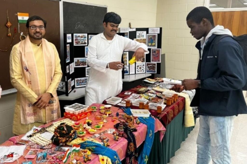 Vivek Singh standing behind table at cultural fair with two other students