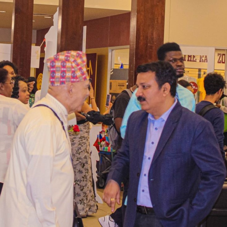 Dr. Kapil talking to colleague in large room of people