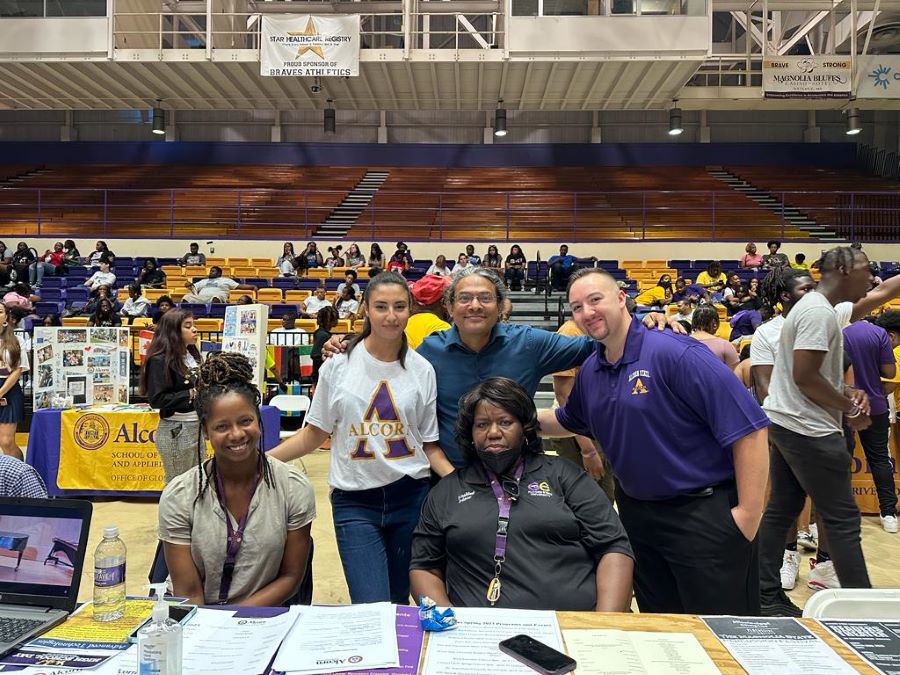 FLTAs in Alcorn State U uniform standing behind table at high school information day