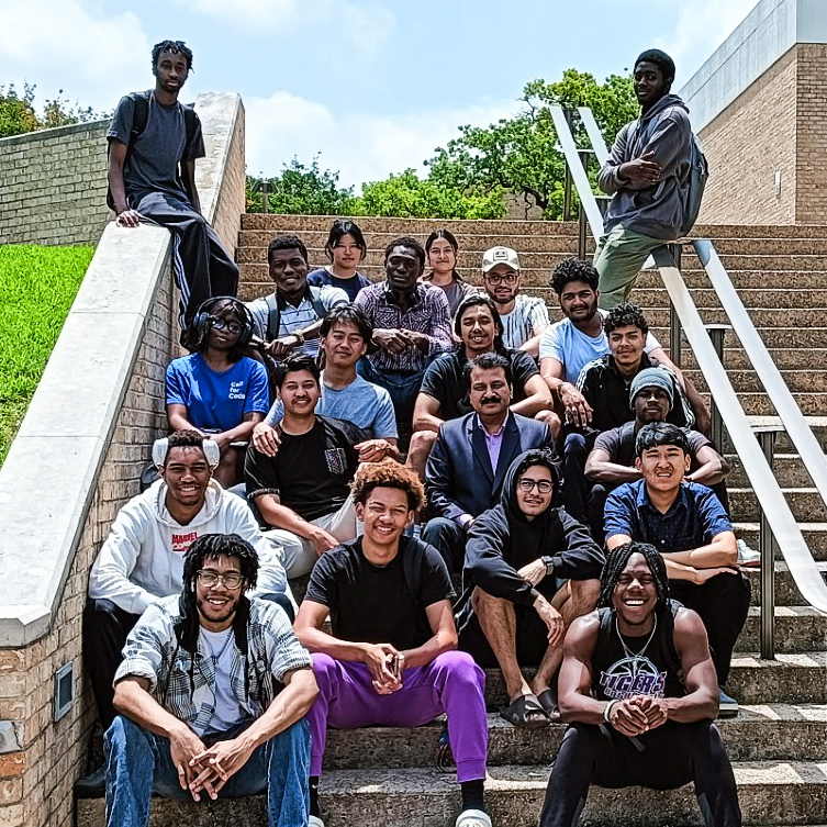 Dr. Kapil sitting on campus steps with students