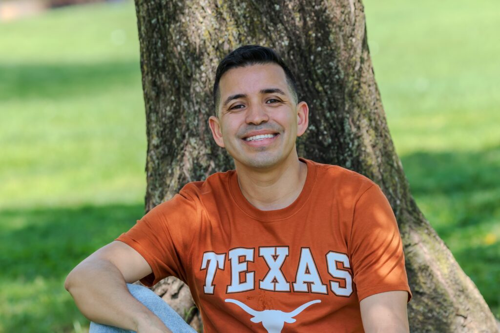 Juan Gonzalez in UT Austin shirt sitting under tree