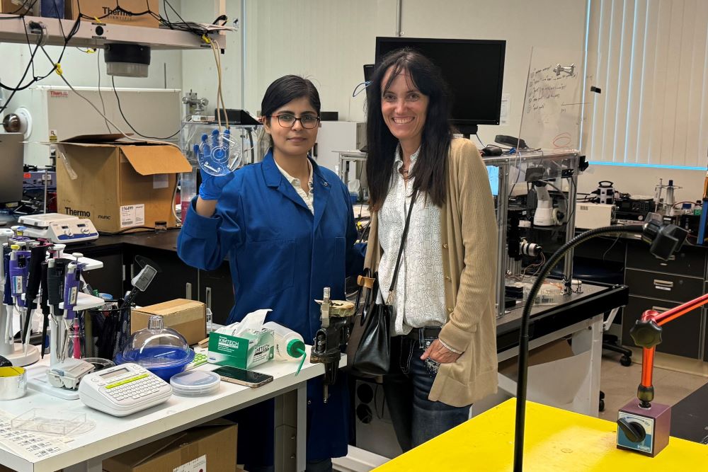 Two women standing in lab holding petri dish