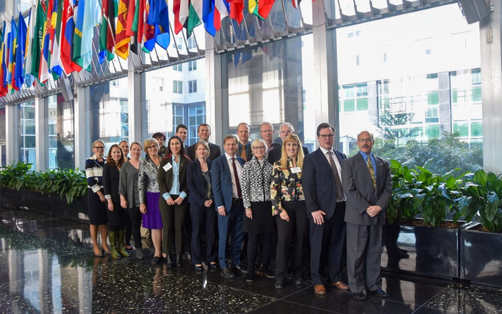 Dr. Michael Sfraga standing in long line with other Arctic scholars underneath flags