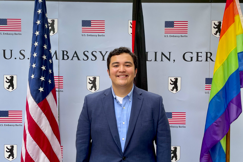 Johnny Zapata standing in front German Embassy step and repeat, American flag and pride glad