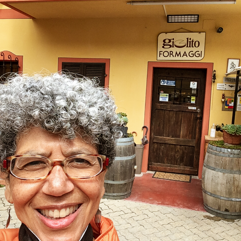 Rafia Zafar in Italy standing outside cheese shop in Italy