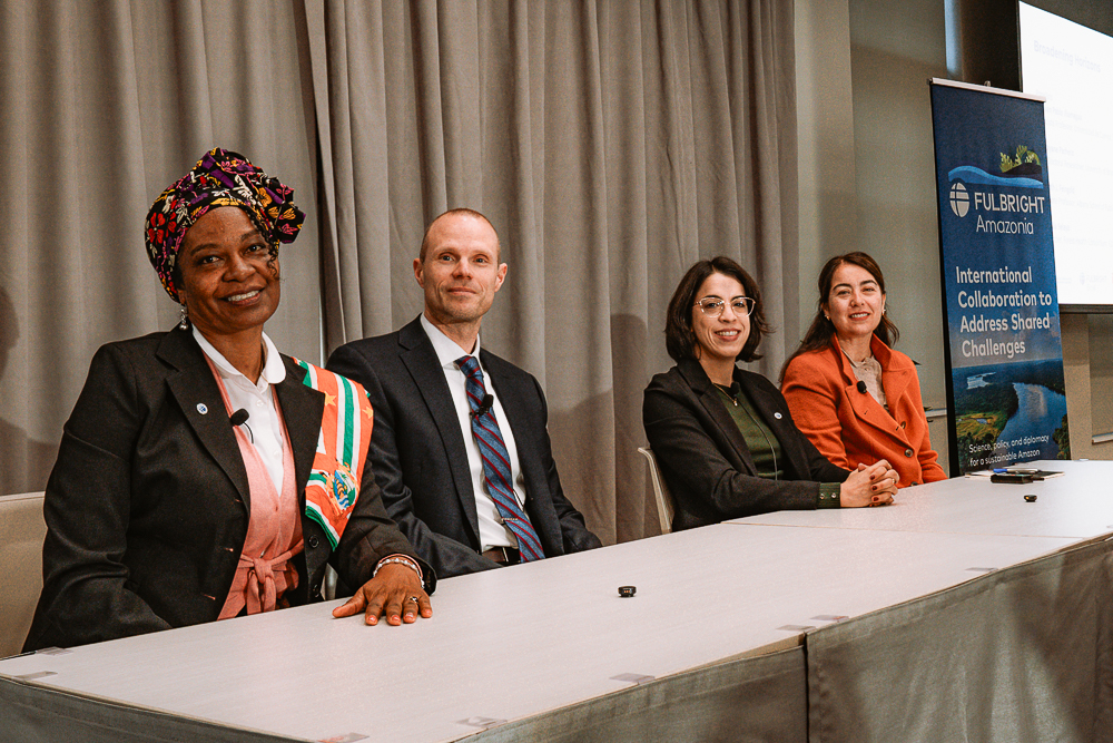 Four panelists seated at a conference table with a Fulbright Amazonia banner in the background.