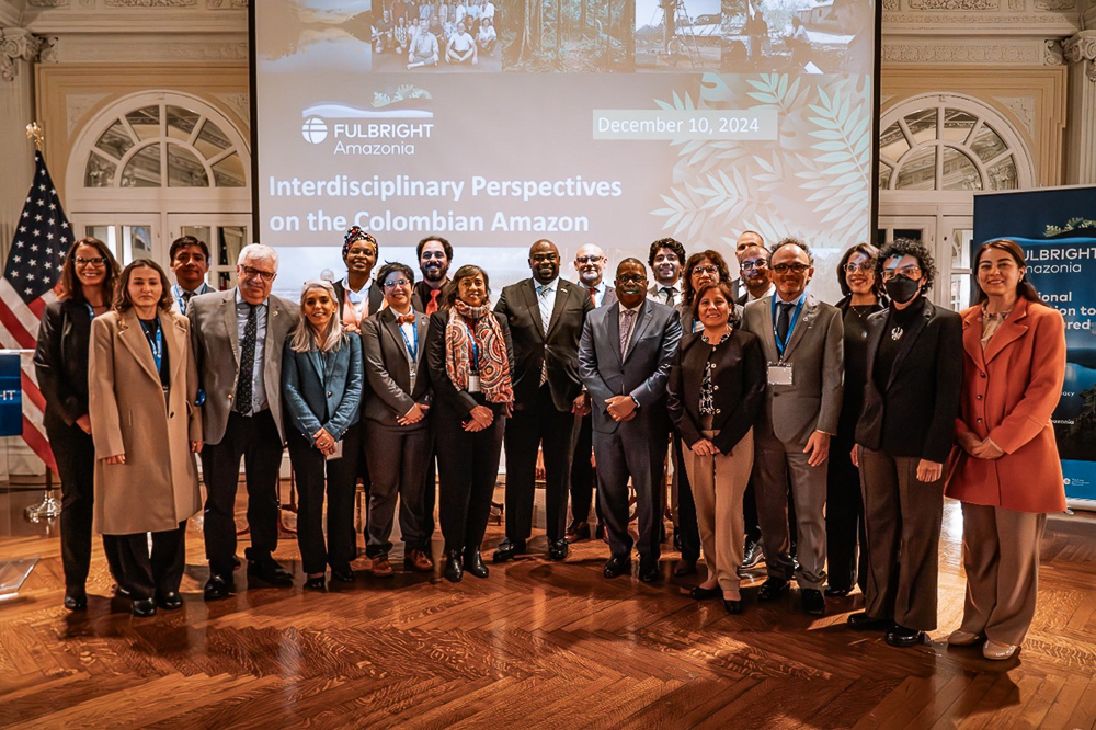 A group of people in formal attire stands together at an event titled "Interdisciplinary Perspectives on the Colombian Amazon".