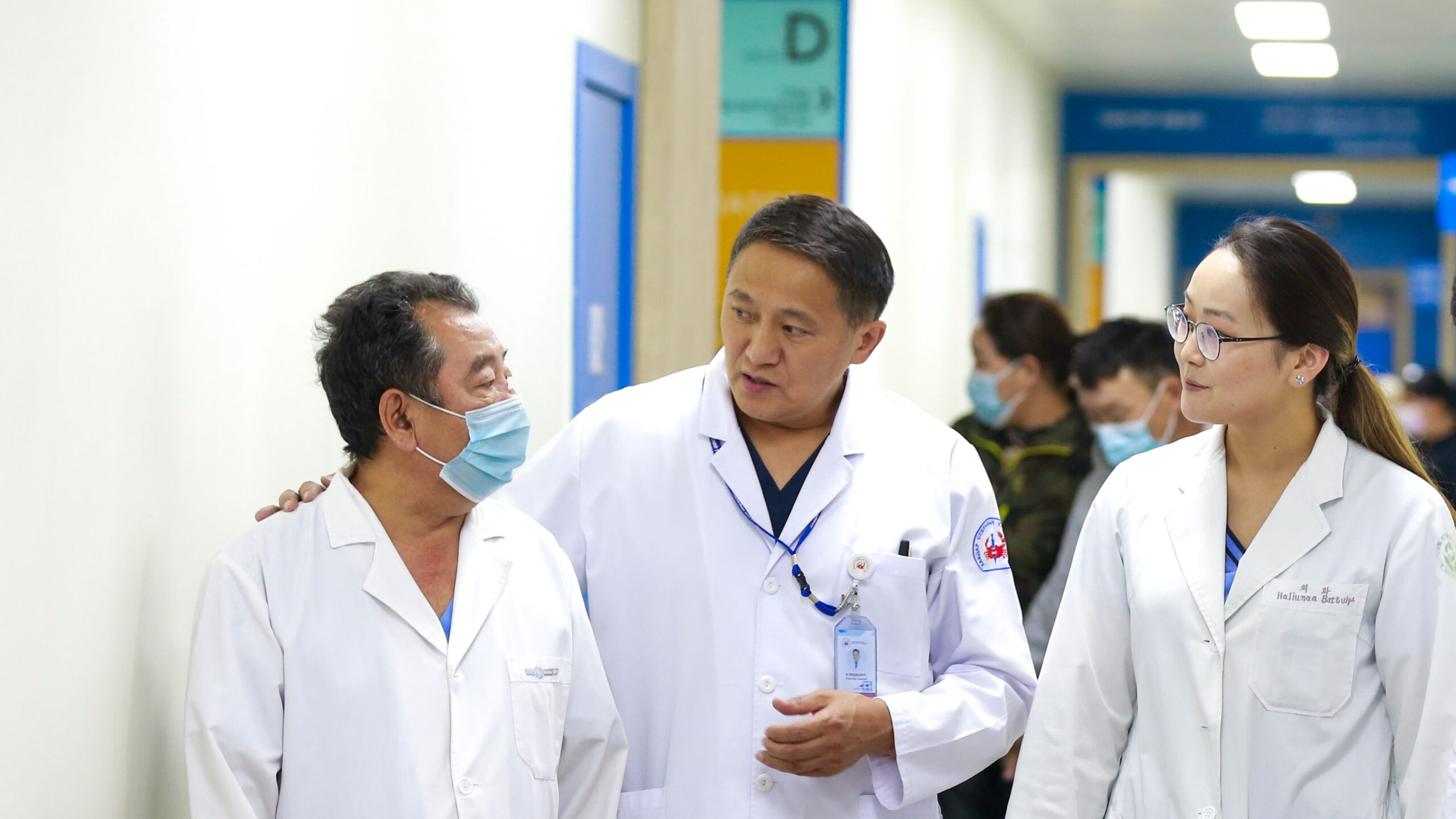 Two doctors standing in hospital corridor talking to patient