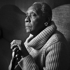 Black and white portrait of Maryse Condé in a turtleneck sweater, holding a cane.