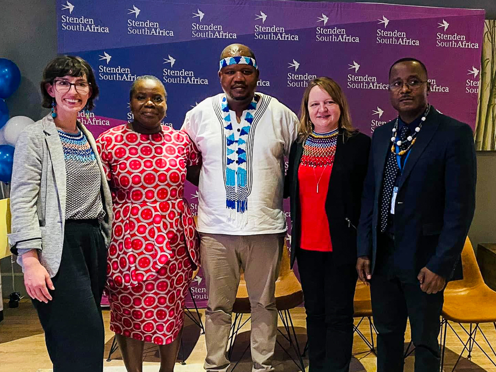 Five people smiling in front of a "Stenden South Africa" backdrop.