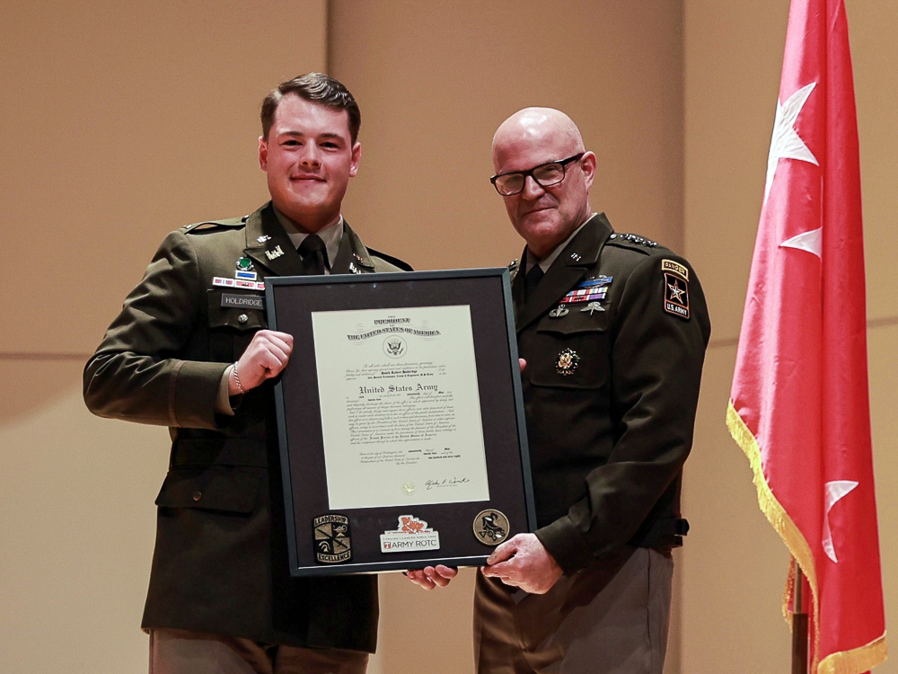 Two men in military uniforms holding a framed document.