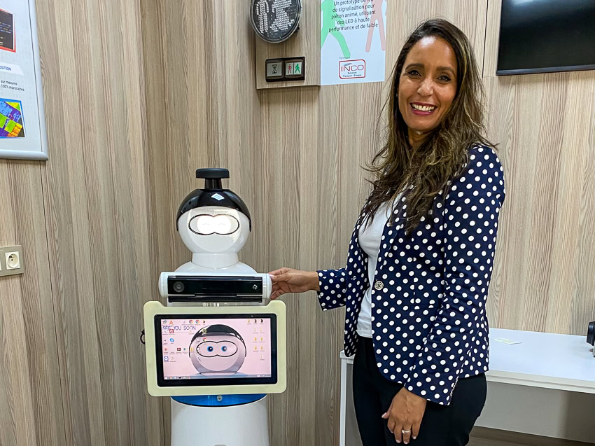 Parks smiling next to a robot with a digital display in an office.