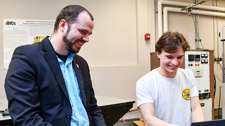 Downey with student in a mechanical engineer lab with technical equipment
