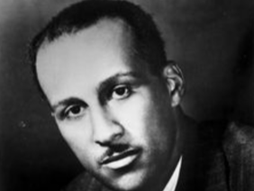 Black and white portrait of Frank Martin Snowden, Jr. with close-cropped hair and a mustache, wearing a suit, in front of a plain gray background
