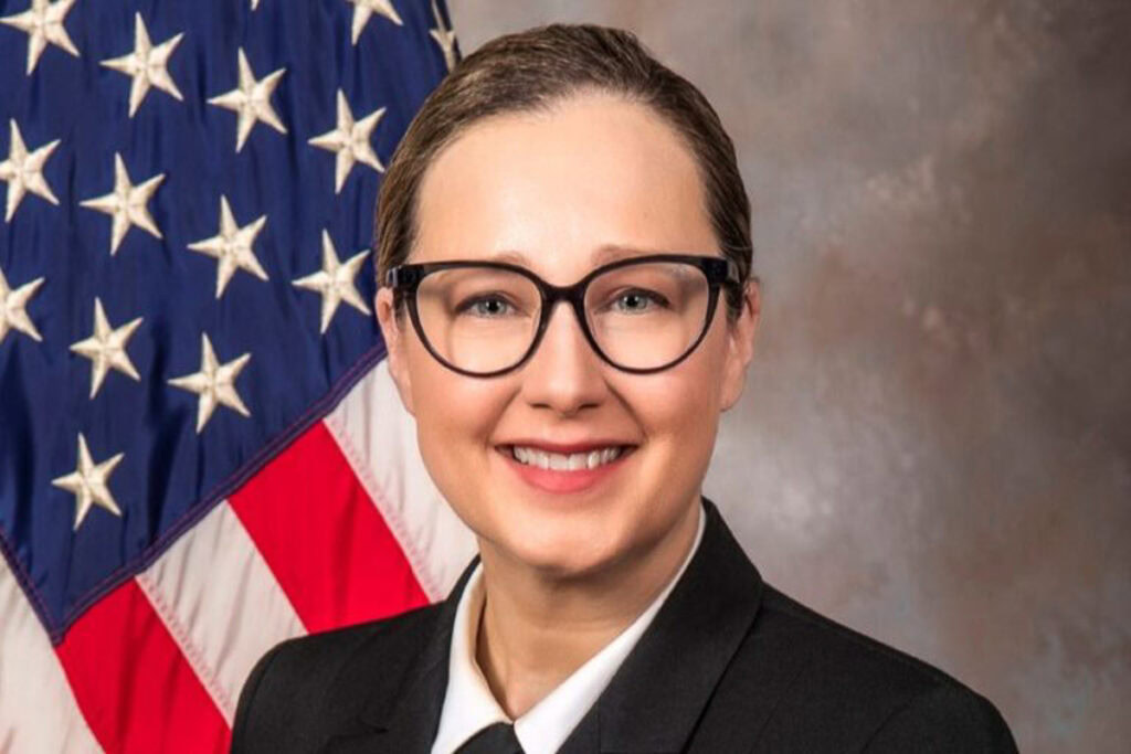 Surgeon and U.S. Navy Captain Tamara Worlton in a formal portrait wearing her U.S. Navy uniform standing in front of an American flag