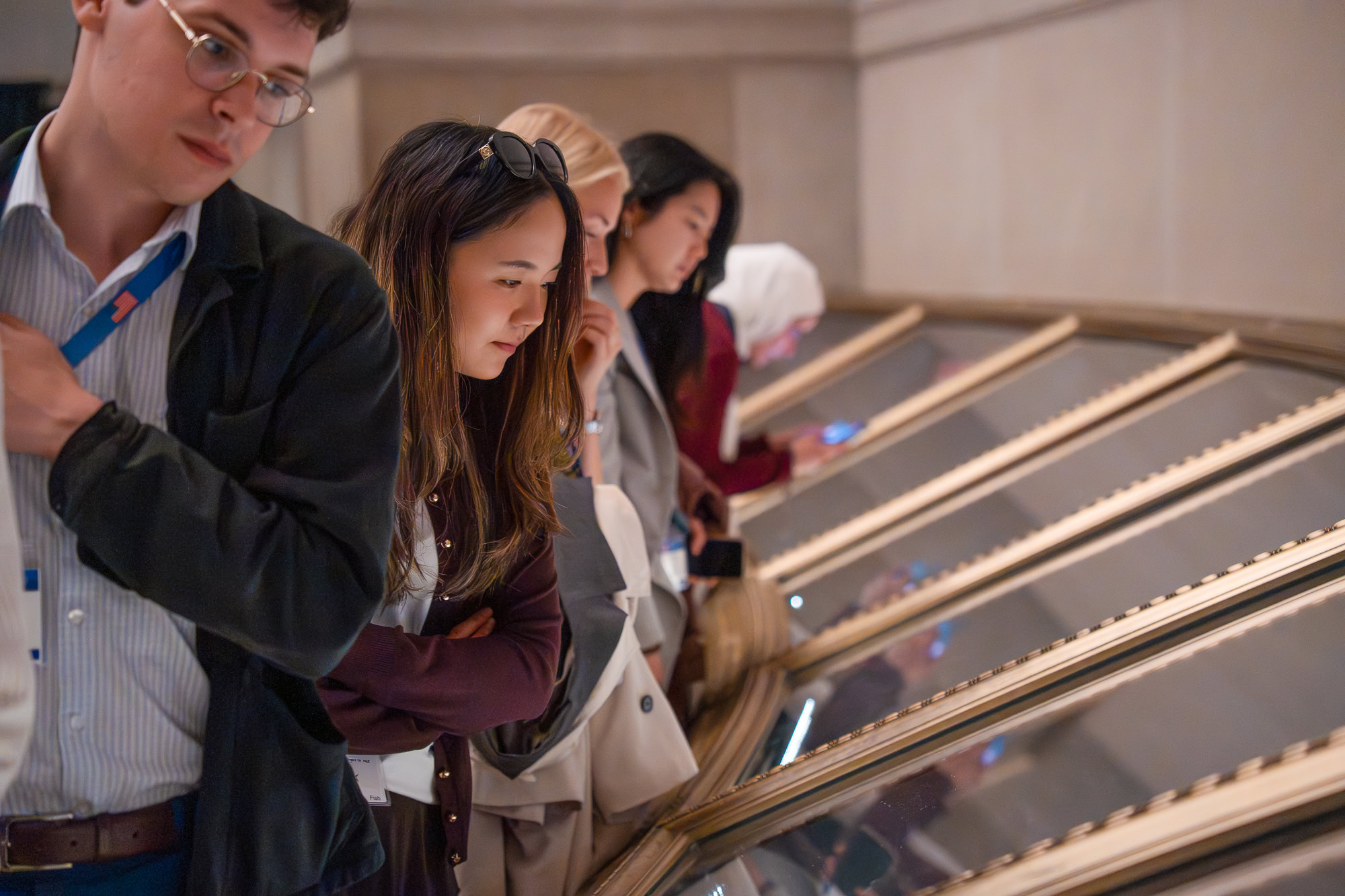 Students looking at display cases with gold frames and protective glass housing America's Charters of Freedom displays