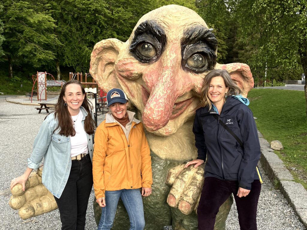Three women standing with a sculpture of a troll in a Norwegian park